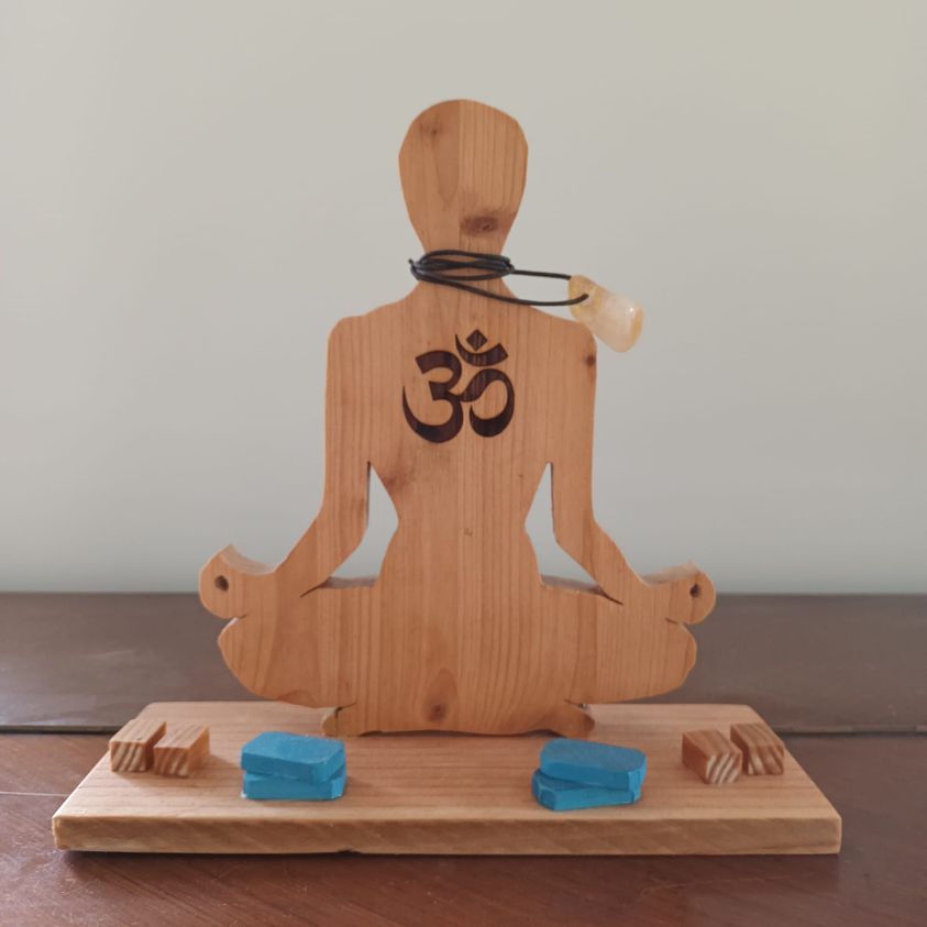 Figurine en bois représentant un yogiste en position de yoga sur son tapis avec ses briques devant lui
